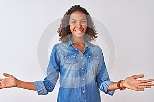 Young brazilian woman wearing denim shirt standing over isolated white background smiling cheerful with open arms as friendly