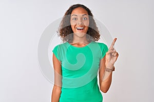 Young brazilian woman wearing green t-shirt standing over isolated white background pointing finger up with successful idea