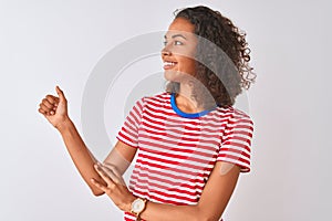 Young brazilian woman wearing red striped t-shirt standing over isolated white background Looking proud, smiling doing thumbs up