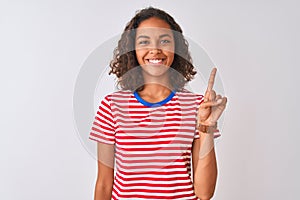 Young brazilian woman wearing red striped t-shirt standing over isolated white background showing and pointing up with finger