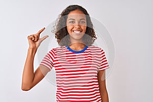 Young brazilian woman wearing red striped t-shirt standing over isolated white background smiling and confident gesturing with
