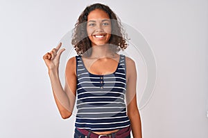 Young brazilian woman wearing striped t-shirt standing over isolated white background smiling and confident gesturing with hand