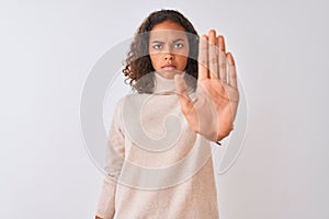 Young brazilian woman wearing turtleneck sweater standing over isolated white background doing stop sing with palm of the hand