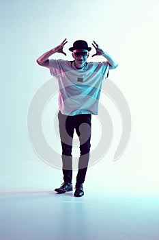 Young breakdancer guy in hat and sunglasses stands in neon light. Dance school poster. Battle competition announcement