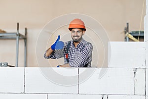 Young bricklayer builder working with autoclaved aerated concrete blocks. Walling, installing bricks on construction site