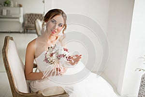 Young bride in a beautiful dress holding a bouquet of flowers in bright white studio. Wedding concept.