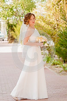 Young bride in a garden in a white dress