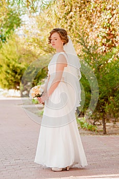 Young bride in a garden in a white dress