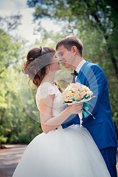 Young bride and groom embracing against the backdrop of the forest the road