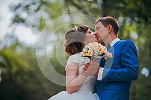 Young bride and groom kissing on the background of the forest