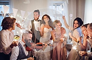 A young bride, groom and other guests dancing and singing on a wedding reception.