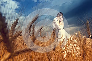 Young bride and groom in wheat field with blue sky