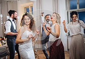 A young bride with other guests dancing on a wedding reception.