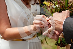 Young bride put wedding ring on the groom`s finger with difficulties, close-up. Wedding ceremony, hardly exchanging. Future