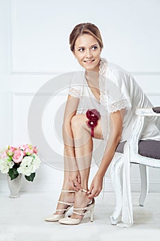 Young bride putting on nude shoes