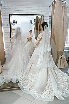 Young bride in salon looking in mirror at her reflection photo
