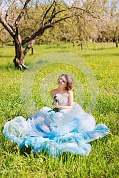 young bride sitting on the grass in the park