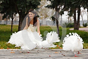 Young bride smiling with white pigeons over park autumn outdoor