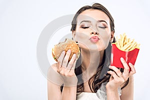 young bride in wedding dress with burger and french fries sending kiss at camera