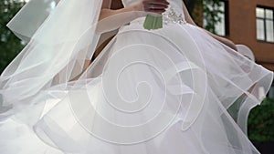 Young bride in wedding dress circling in a city. White luxury gown fashion