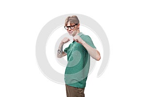 young bright ginger man with a tattoo on his arm dressed in a green short sleeve t-shirt posing on a white background