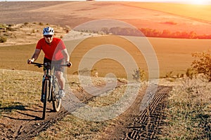 Young bright man on mountain bike riding in autumn landscape