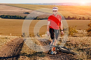 Young bright man on mountain bike riding in autumn landscape