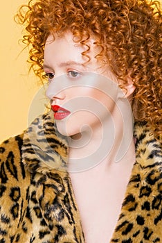 Young bright model with red curly hair and a leopard trend coat