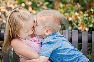 Young Brother Kisses Sister on the Cheek At The Park