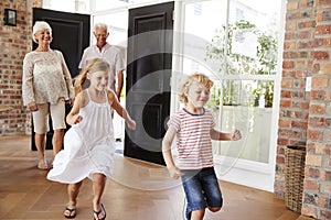 Young brother and sister arriving home with grandparents