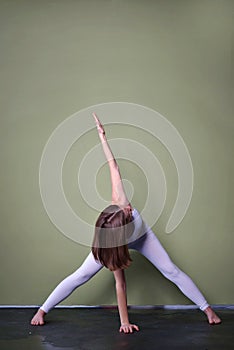 young brown-haired girl in oigi pose - Parivrata prasarita padottanasana - Bend with legs wide apart with twisting.