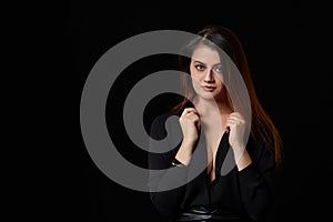 A young brown-haired woman in a black shirt with a beautiful open chest. on a black isolated background