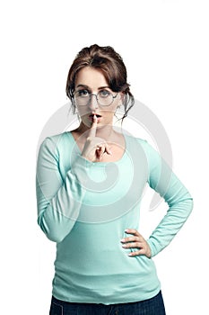 A young brown-haired woman  in a mint-colored jumper and in round glasses  narrowed her eyes and held her index finger at the lip