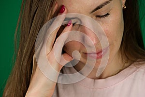 Young brown-haired woman with wool scarf has toothache, emotions of a young girl on a green background chromakey