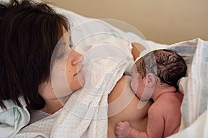 Young brown woman breastfeeding her newborn daughter. Concept of mothers