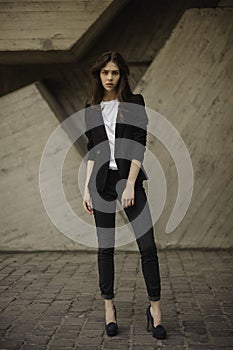 Young brunet woman standing outside in black jacket, jeans wearing hills . horizontal