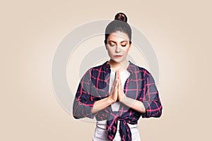 Young brunete woman practising yoga, holding hands in namaste and keeping her eyes closed. Caucasian girl meditating