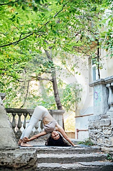 Young brunette asian woman practicing yoga during workout in park