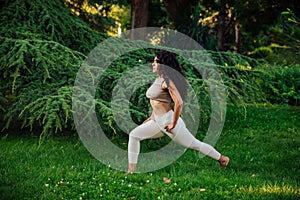 Young brunette asian woman practicing yoga during workout in park