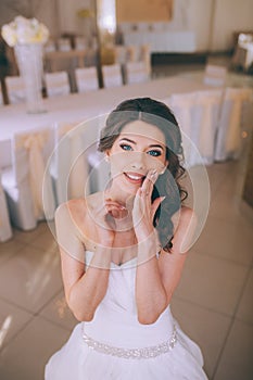 A young brunette bride poses for the camera. An emotional smiling bride