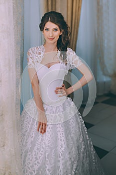 A young brunette bride poses for the camera. An emotional smiling bride