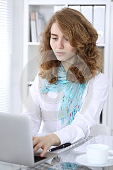 Young brunette business woman looks like a student girl working in office. Caucasian girl happy at work and too busy