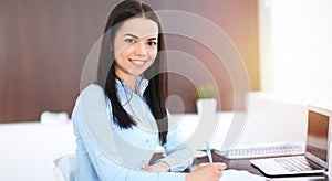 Young brunette business woman looks like a student girl working in office. Hispanic or latin american girl happy at work