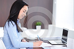 Young brunette business woman looks like a student girl working in office. Hispanic or latin american girl happy at work