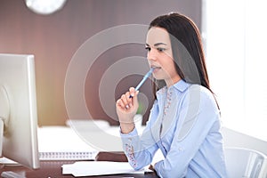 Young brunette business woman looks like a student girl working in office. Hispanic or latin american girl happy at work