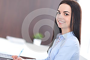 Young brunette business woman looks like a student girl working in office. Hispanic or latin american girl happy at work