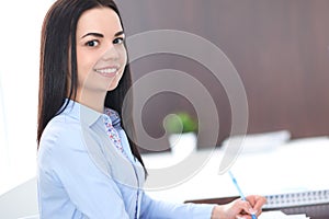 Young brunette business woman looks like a student girl working in office. Hispanic or latin american girl happy at work