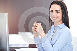 Young brunette business woman looks like a student girl working in office. Hispanic or latin american girl happy at work