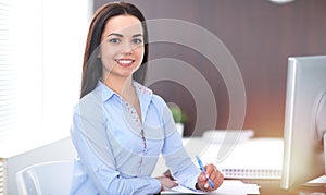 Young brunette business woman looks like a student girl working in office. Hispanic or latin american girl happy at work