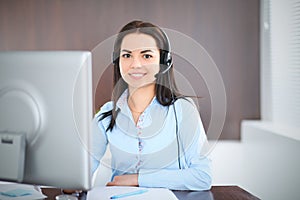 Young brunette business woman looks like a student girl working in office. Hispanic or latin american girl talking by